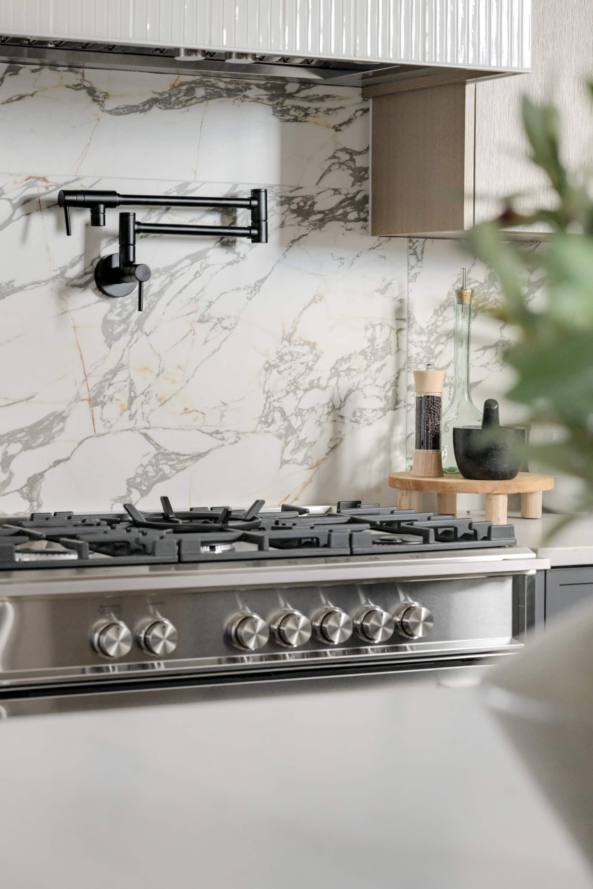 Modern kitchen stove with marble backsplash and black faucet in Cedar & Stone home by White Wolf.