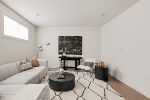 Modern living room with light gray sectional, geometric rug, and contemporary furniture in a clean,白.