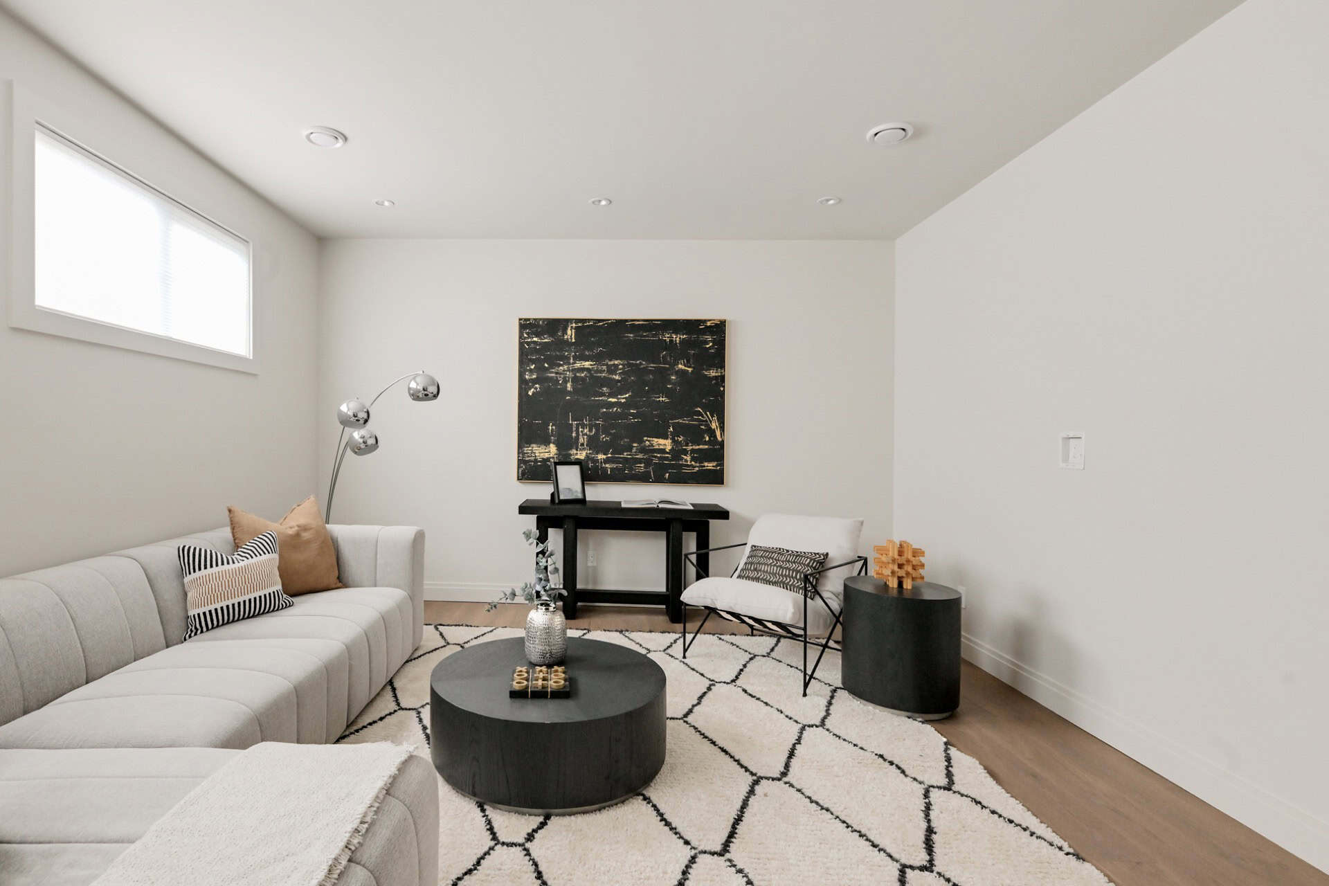 Modern living room with light gray sectional, geometric rug, and contemporary furniture in a clean,白.