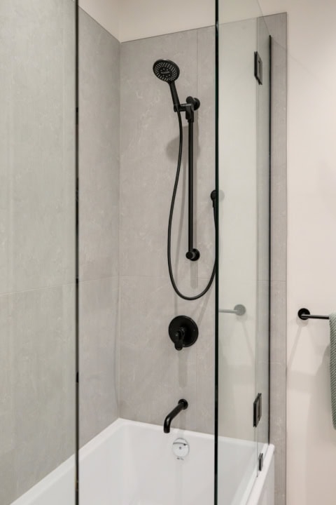 Modern shower with black matte fixtures in a glass-walled bathroom.