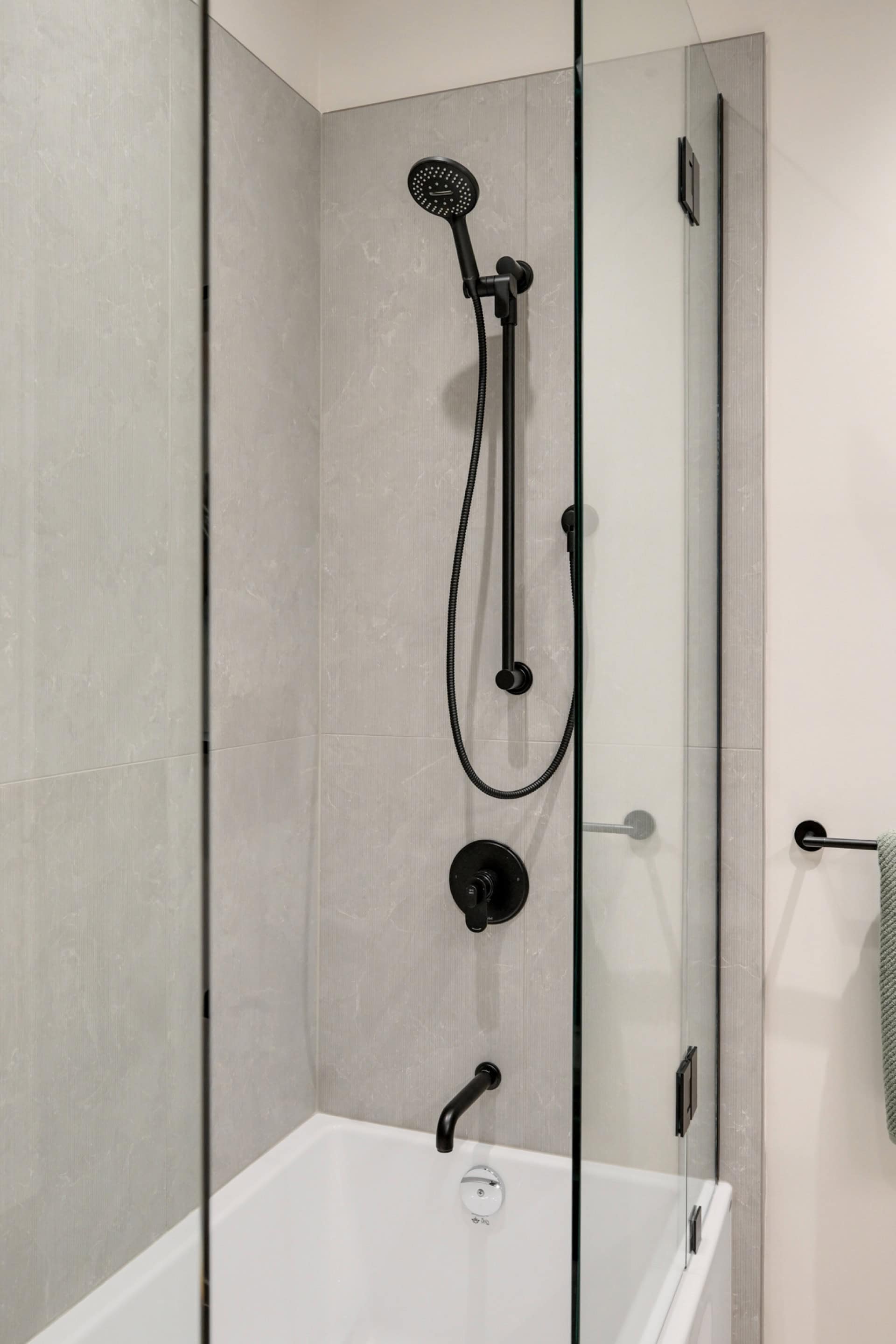 Modern shower with black matte fixtures in a glass-walled bathroom.