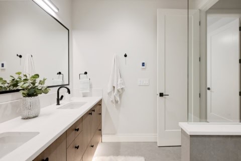 Elegant white bathroom with double vanity, large mirror, and sliding door.