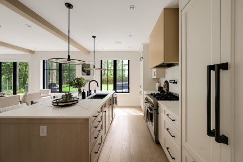 Modern white kitchen with island, pendant lights, and stainless steel appliances in Victoria BC home.