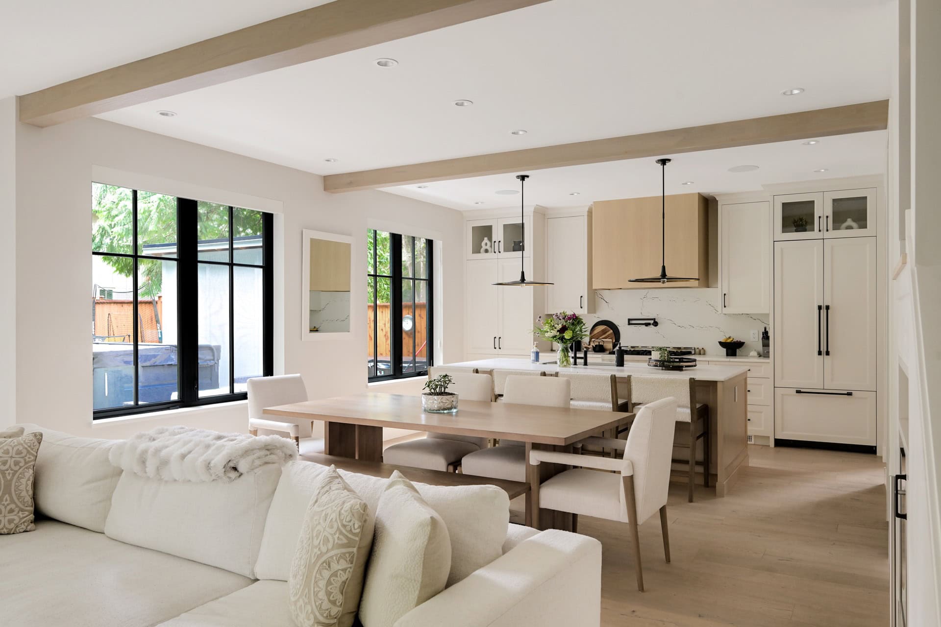 Open-concept kitchen and living area with light wood beams and modern white cabinetry.