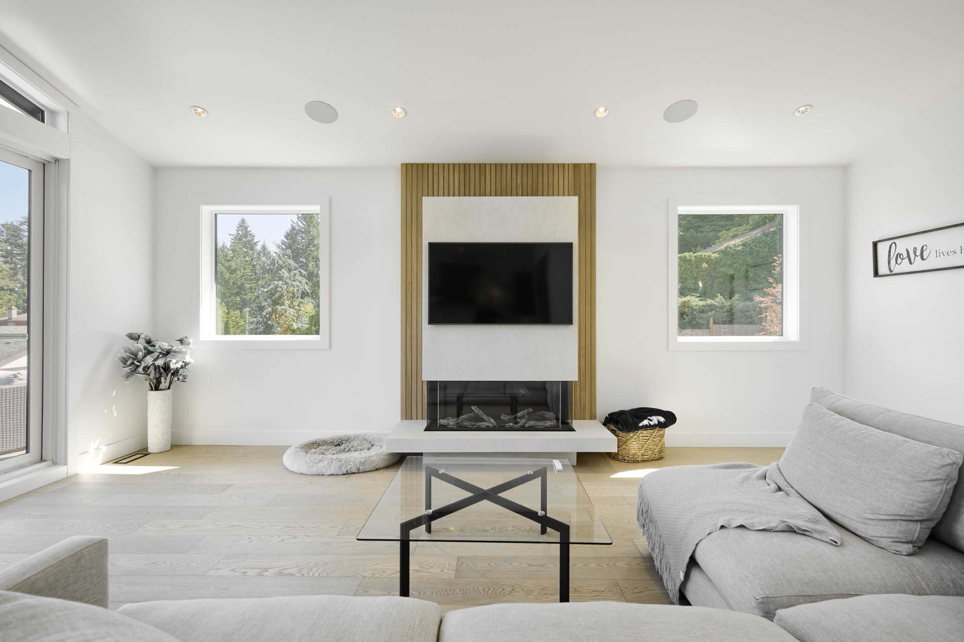 Modern living room with a central fireplace and large windows in a bright, minimalist interior.