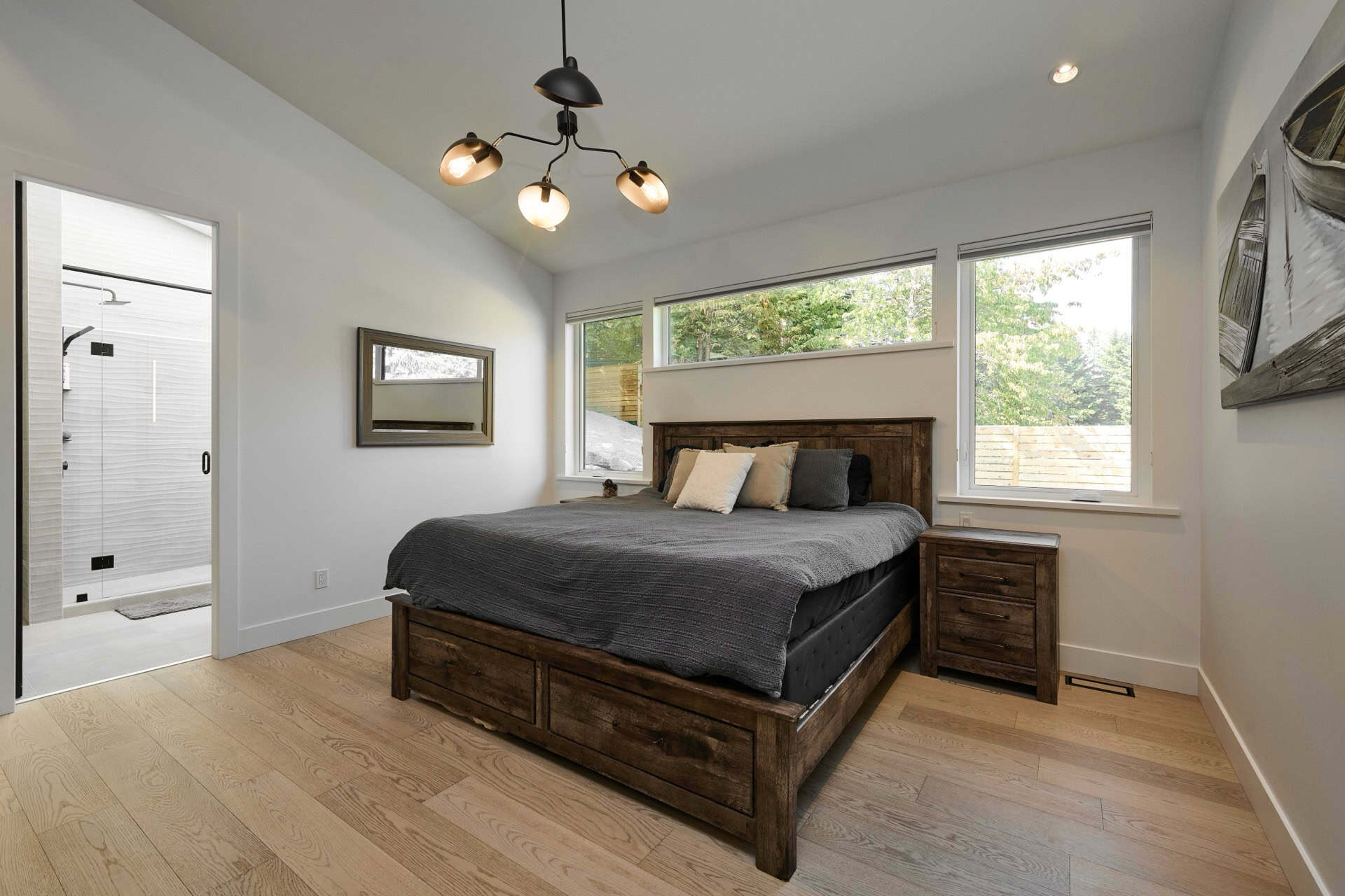 Bright bedroom with wooden bed frame and large windows in a modern home.