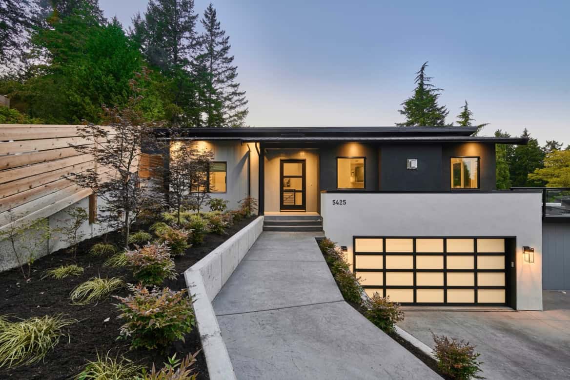 Grey and black modern duplex style home with landscaped path to entrance and a two-car garage.