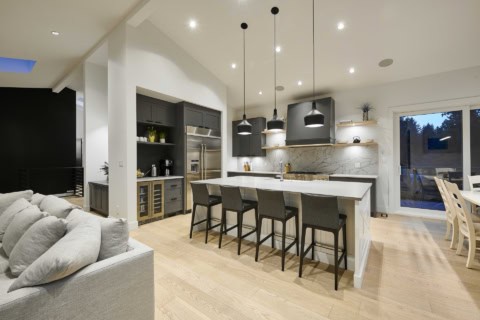 Modern open-concept kitchen in a white-wanded home with island and black pendant lights.