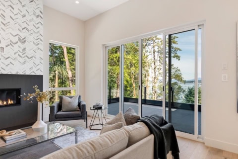Modern living room with large glass doors opening to a balcony and lake views.