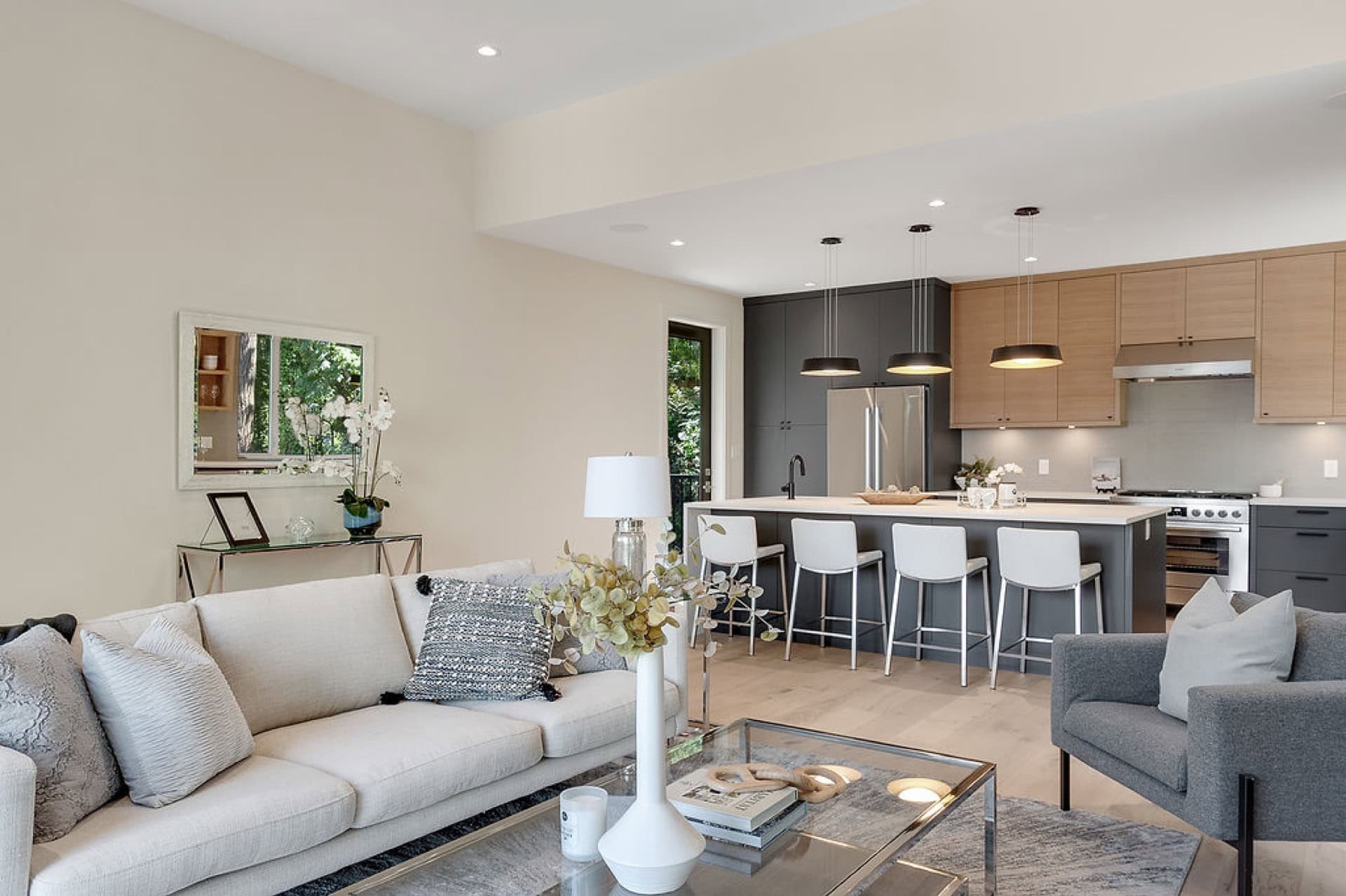 Bright open living kitchen area with light gray sofa, island, and contemporary furniture.