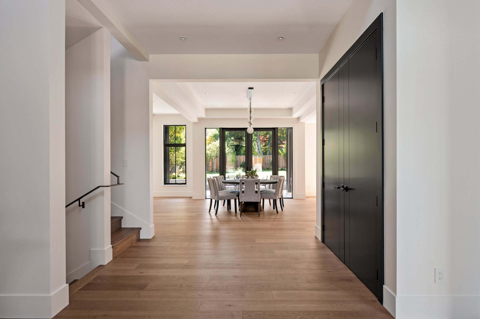 Bright open-plan dining area in a new Victoria BC home with large windows and hardwood floors.