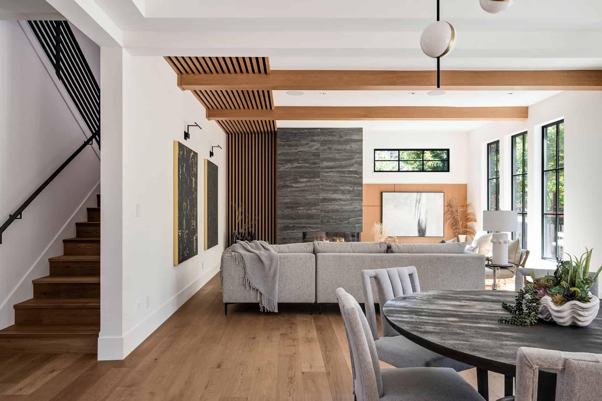Modern living room with wood beams, stone fireplace, and large windows in a Victoria BC custom home.
