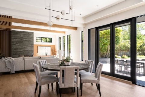 Open-plan dining room with grey chairs and large black-framed glass doors.