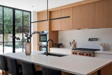Modern Victoria BC kitchen by White Wolf Homes with wood cabinets, large window, and island.