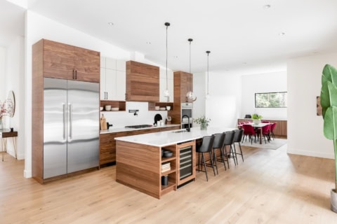 Open-concept kitchen with wooden cabinetry and island in Woodside project by White Wolf Homes.