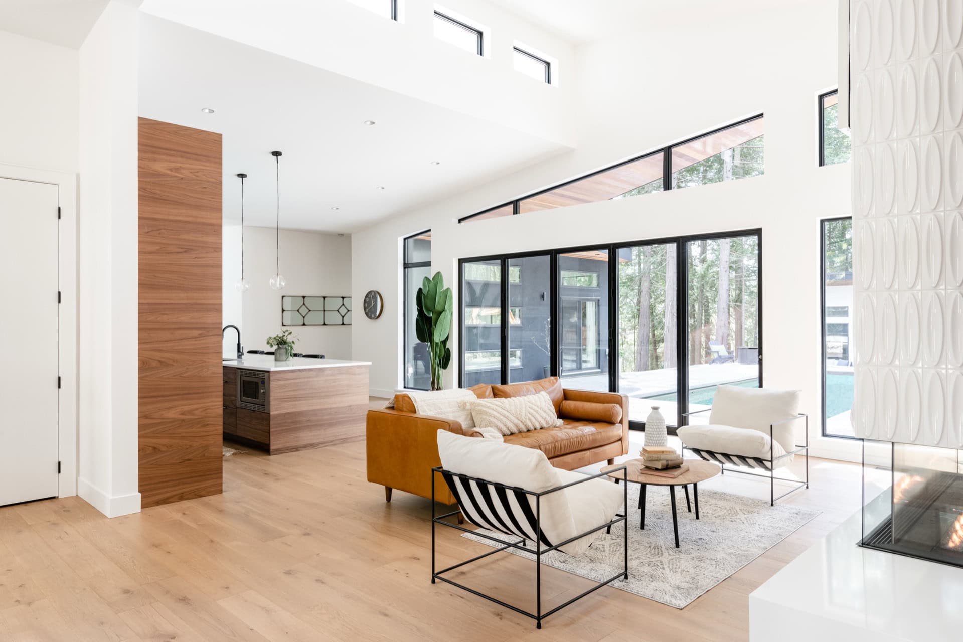 Bright modern living room with open kitchen, large windows, and stylish seating at White Wolf Homes.
