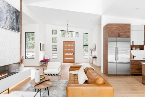 Modern open-concept living room with caramel leather sofa and contemporary kitchen in Victoria BC.