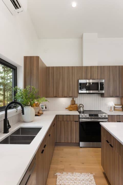 Modern kitchen with wood veneer cabinetry, white countertops, and stainless steel appliances in Wood.