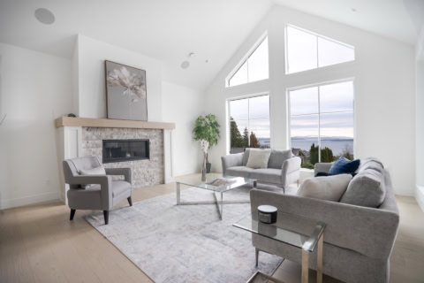Bright living room with vaulted windows, modern furniture and fireplace in Victoria BC home.