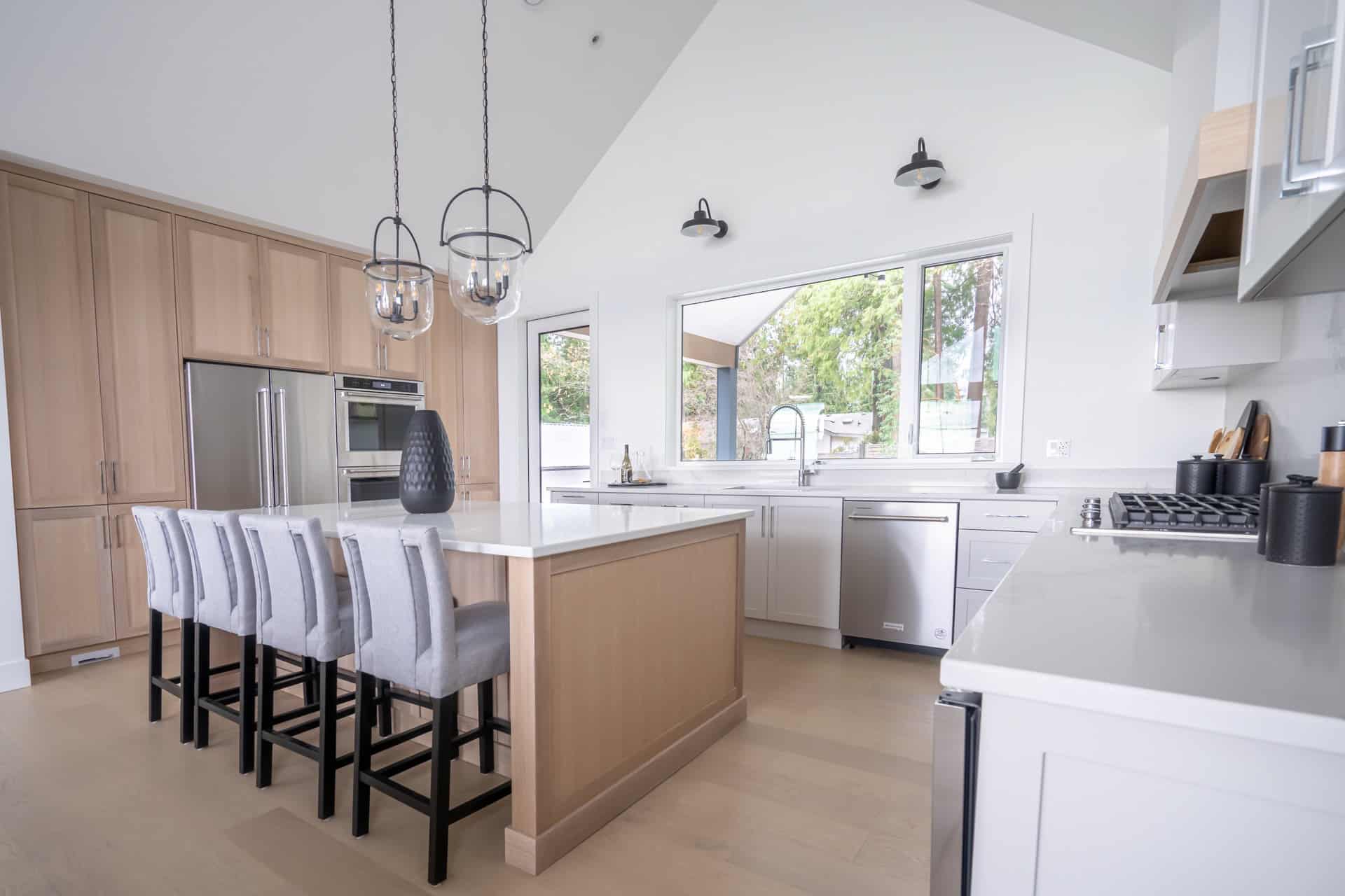 Modern kitchen by White Wolf Homes in Victoria BC with island, stainless appliances, white cabinets,.