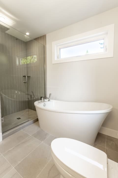 Modern bathroom with freestanding tub and glass shower in a Victoria BC home.