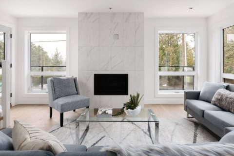 Modern living room with stone fireplace, large windows, and minimalist seating in a bright Victoria,.