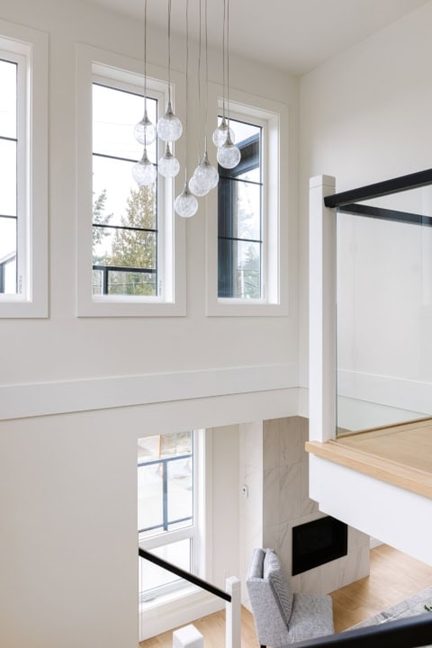 Bright, airy interior with large windows, chandelier, and modern staircase at Arbutus Rise by White.