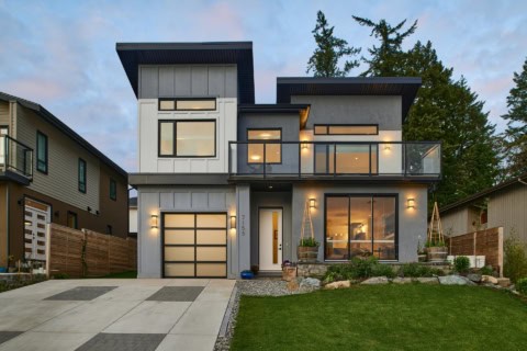 Modern two-story home exterior with large glass railing balcony and landscaped yard.
