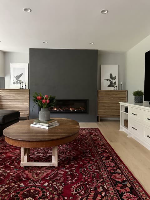 Modern living room with fireplace, dark accent wall, and wooden furnishings.