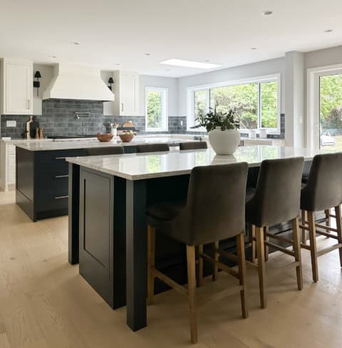 Modern kitchen with large island, white cabinets, dark island base, and gray subway tile backsplash.