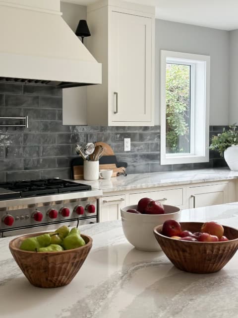 Modern white kitchen with marble island and gray subway backsplash in Victoria BC home.