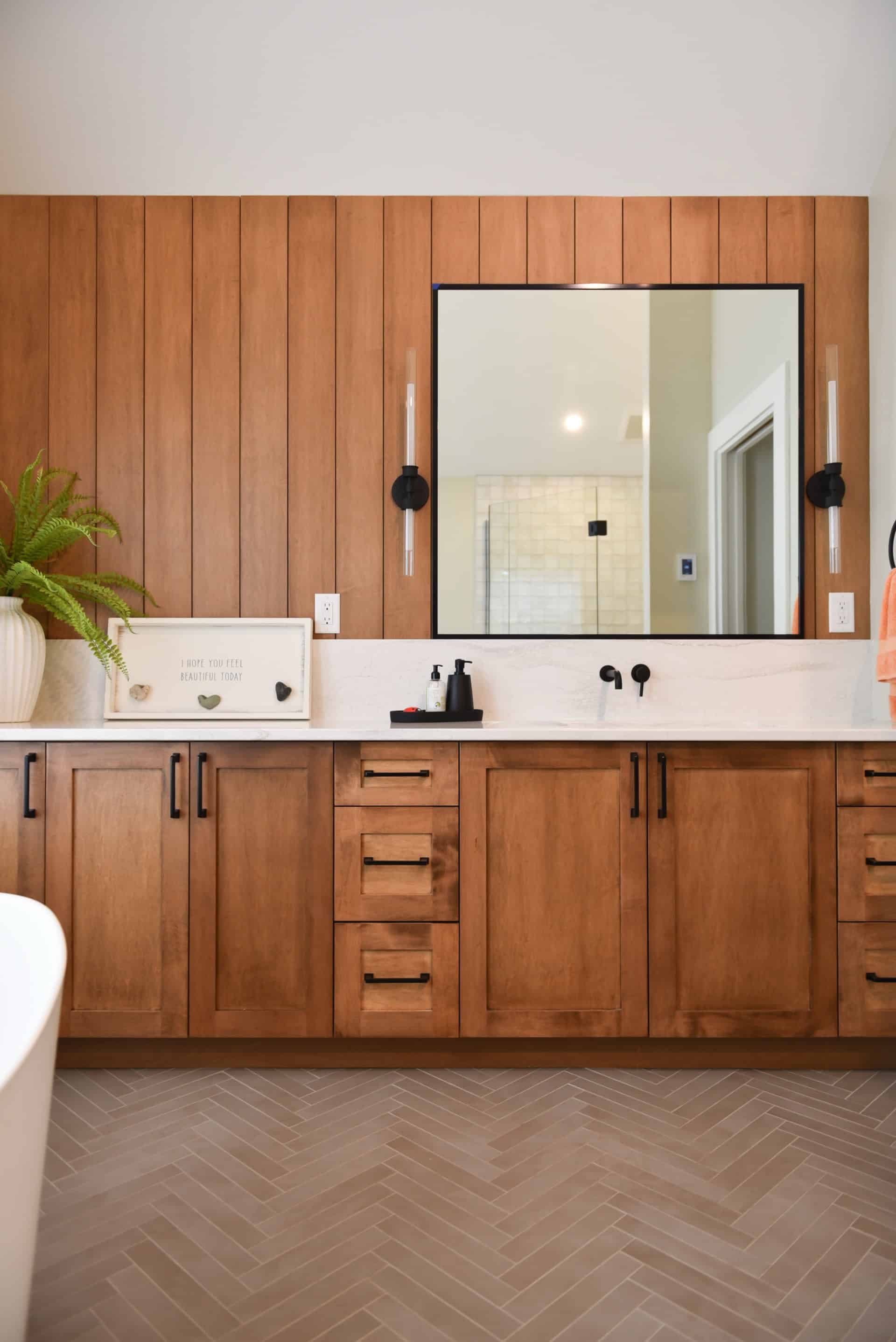 Modern bathroom vanity with wooden cabinetry and large mirror in Victoria BC home.