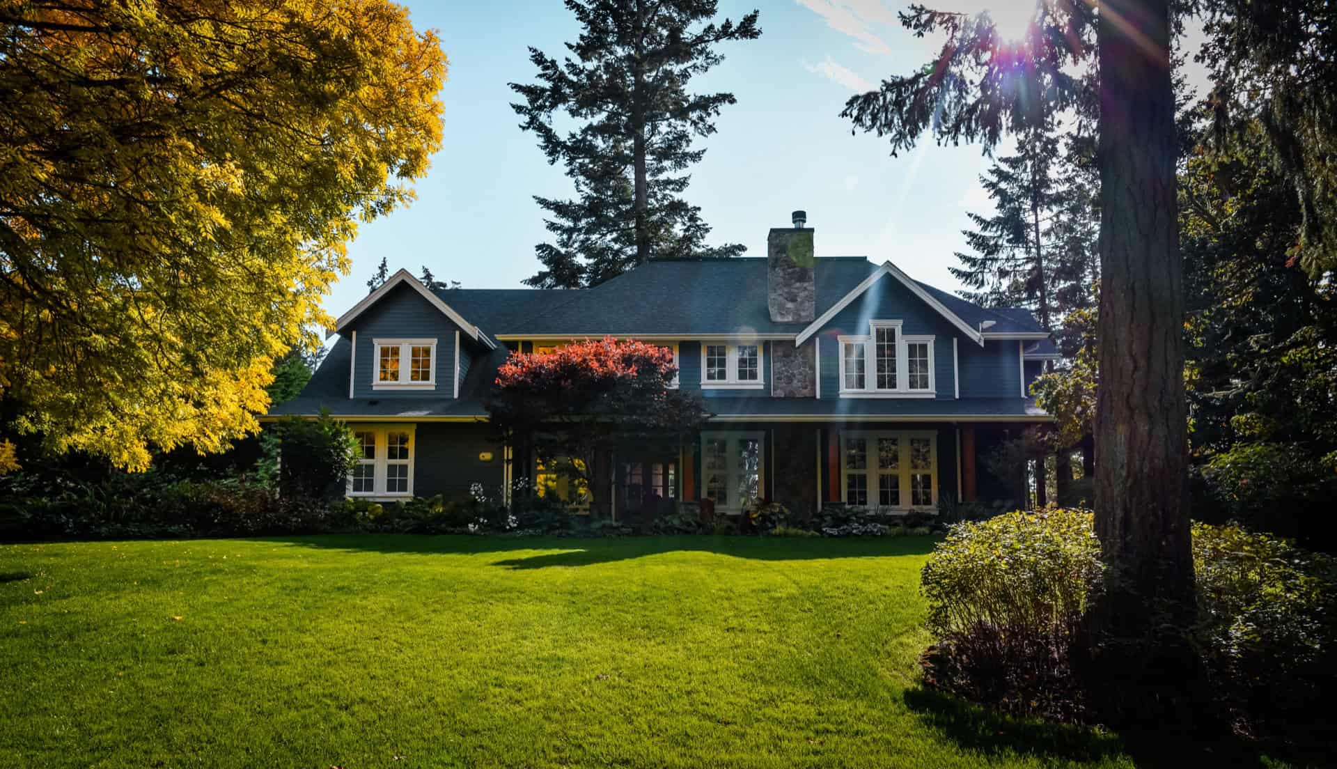Victoria BC custom home by White Wolf Homes with lush green lawn and trees.