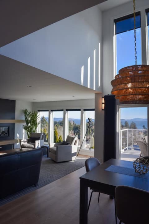 Bright modern living room with large windows and balcony views, open dining area.