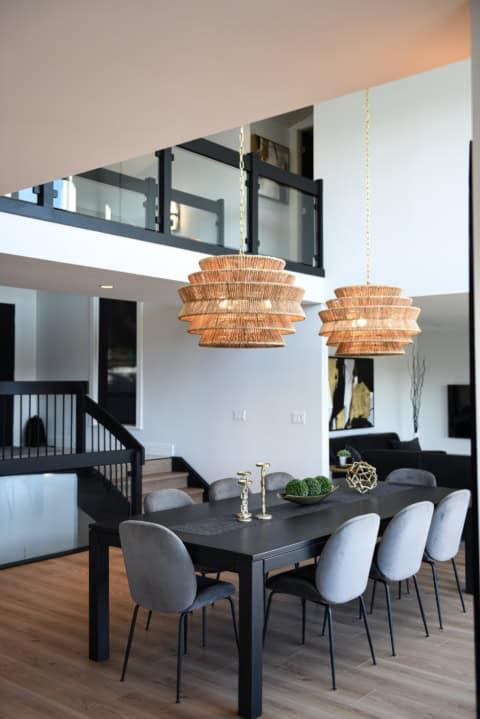Modern dining room with black table, gray chairs, and woven pendant lights.