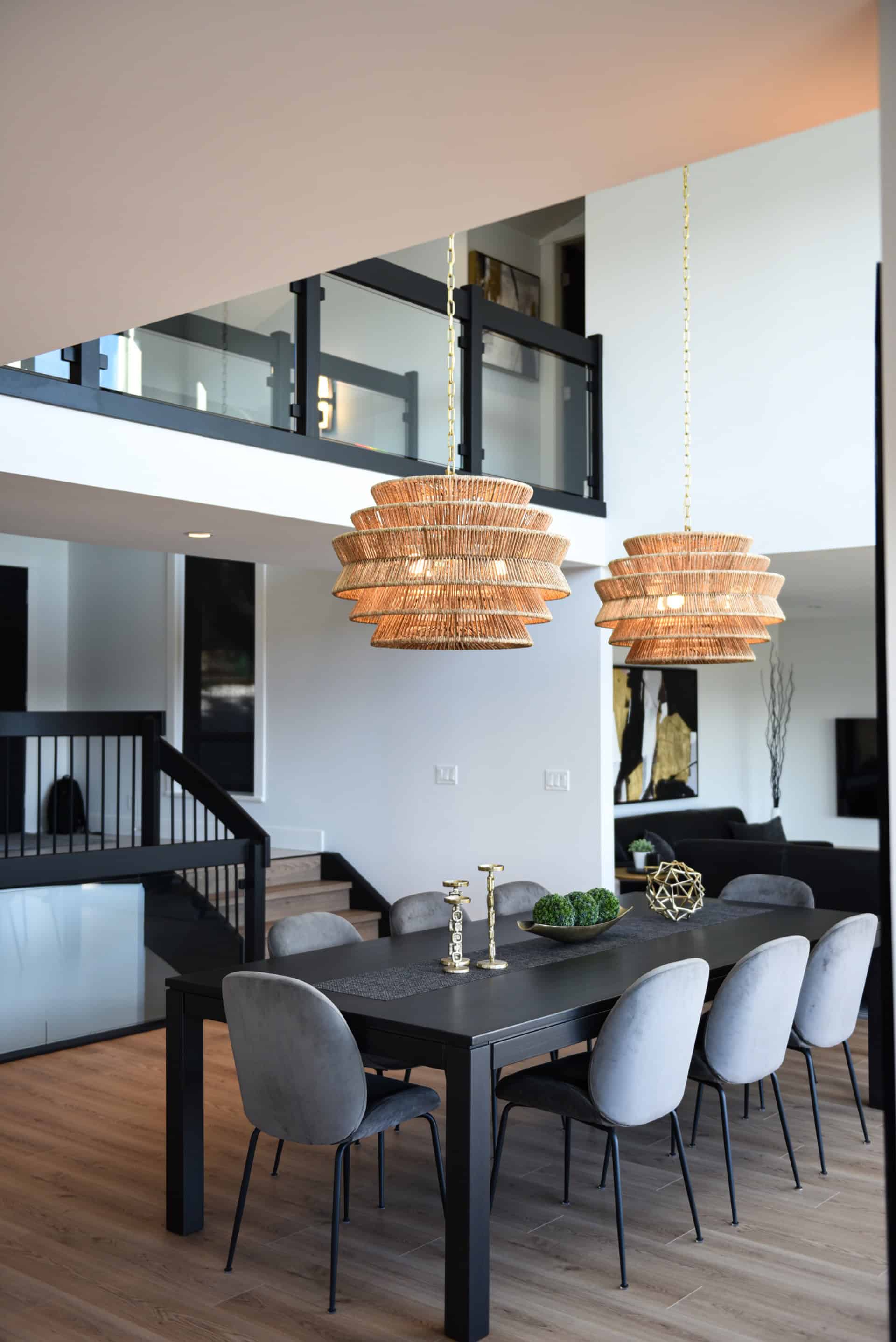 Modern dining room with black table, gray chairs, and woven pendant lights.