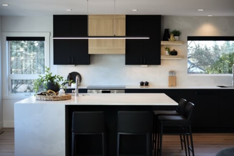 Modern kitchen with black cabinets, white island, and large windows.