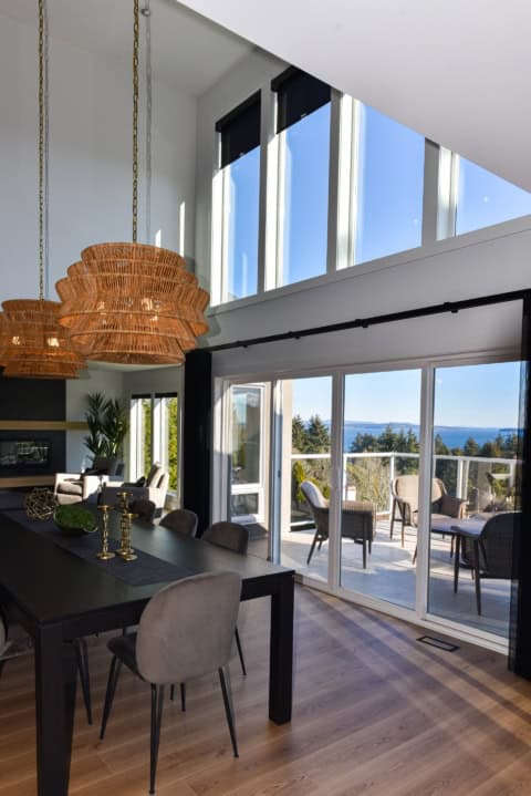 Bright dining area with large windows and balcony view in modern Victoria home.