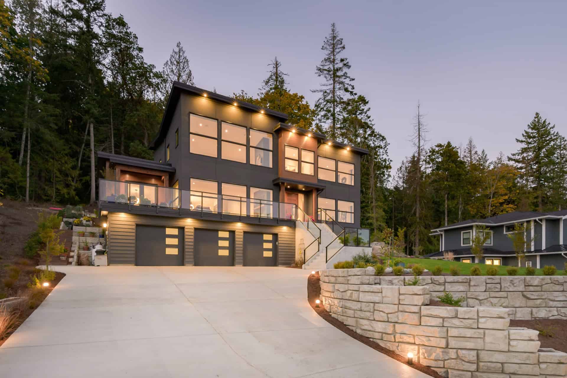 Modern custom home by White Wolf Homes in Victoria BC with dark facade, large windows, and driveway.